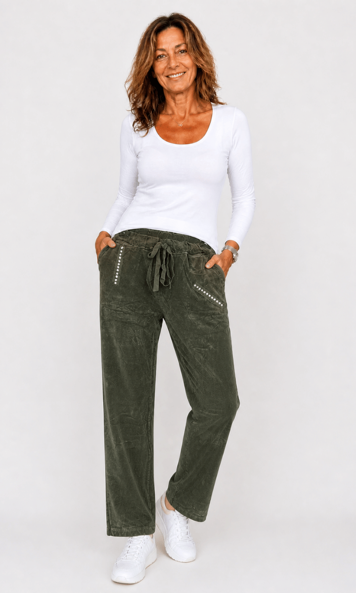 Woman wearing a white top and green pants on a white background