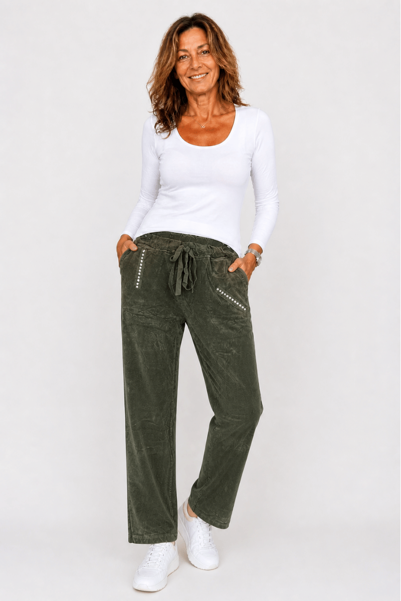 Woman wearing a white top and green pants on a white background