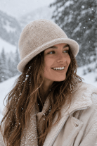 Woman wearing a beige hat and coat in a snowy landscape
